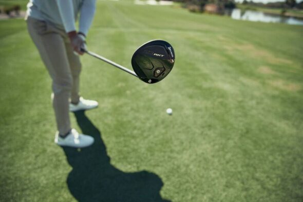 Golfer holding a Srixon ZXi RKT driver beside a teed golf ball on the course.